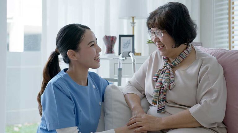 A senior resident sitting in a cozy living room with a small dog resting beside them on a couch.
