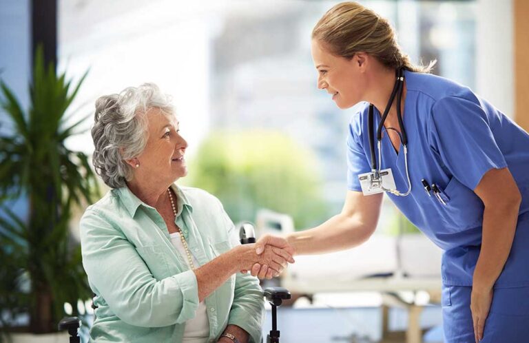 Nurse reviewing medications with an older resident in a bright assisted living room.